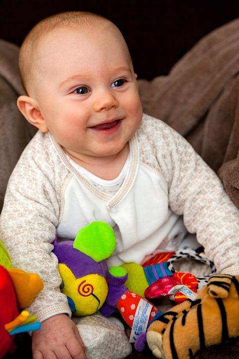 Smějící se kojenec s plyšovými hračkami