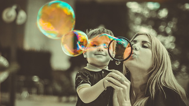 Na obrázku je chlapec s blonďatou ženou, pravděpodobně matkou a foukají bubliny.