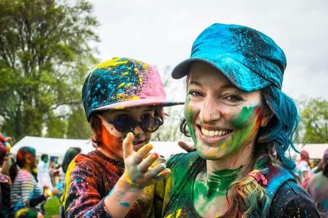 Maminka s dítětem jsou na festivalu barev - jsou pomalovaní barvami a šťastní