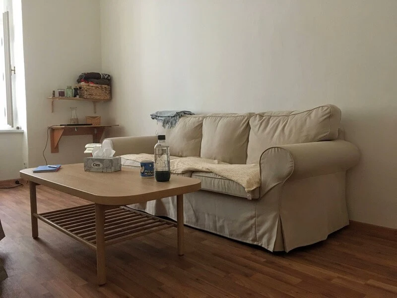 Terapeutická ordinace s bílým gaučem, dřevěným stolkem, vodou a papírovými kapesníčky
